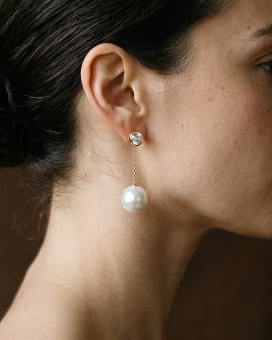 A round white pearl hanging on a fine gold chain from a diamond stud